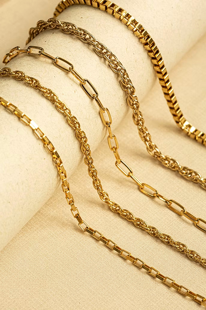 Five yellow-gold chain styles on a display roll